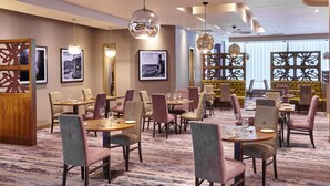 A dining area with multiple tables and chairs, framed pictures on the walls, and decorative lighting fixtures.