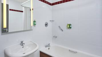 Un baño con un lavabo blanco, una bañera y una ducha. Hay botellas verdes en la pared.