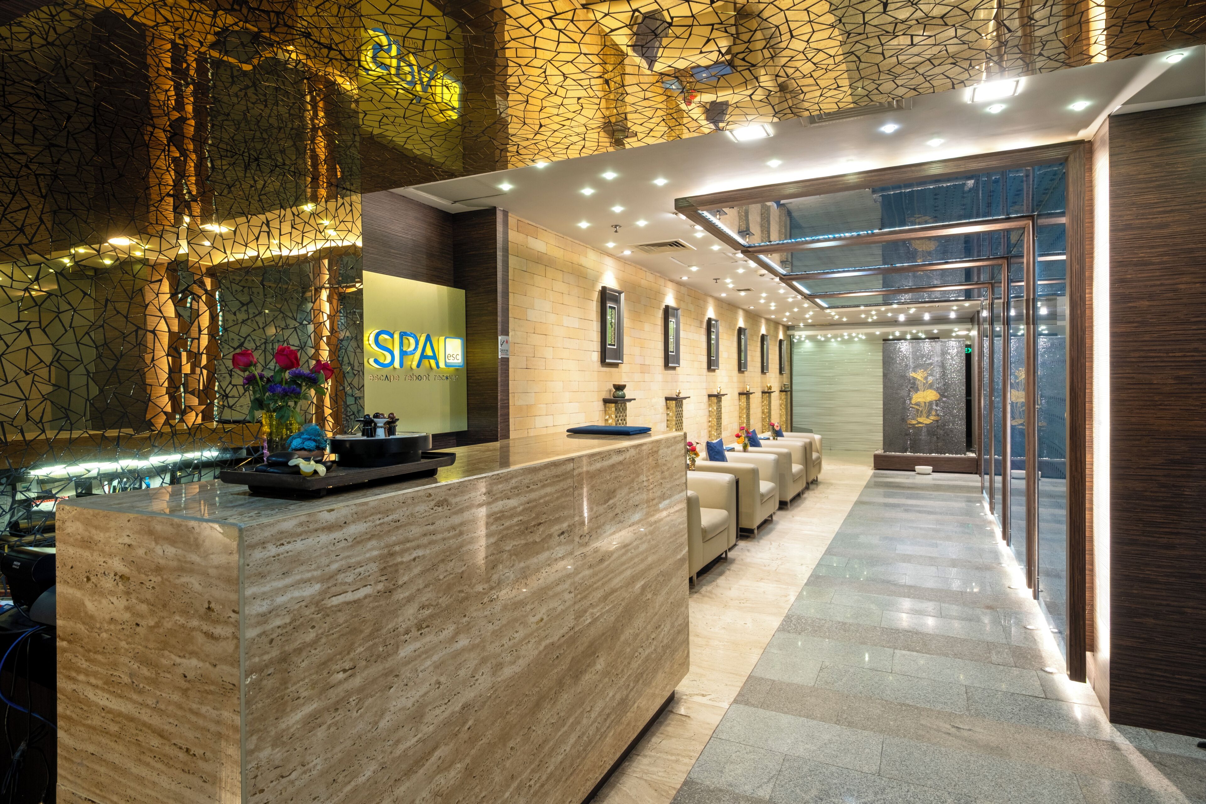A hotel reception area with a reception desk, seating area, and a wall with framed pictures.