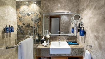 A modern bathroom with a glass shower enclosure, a white sink, and a mirror with a round mirror above it.