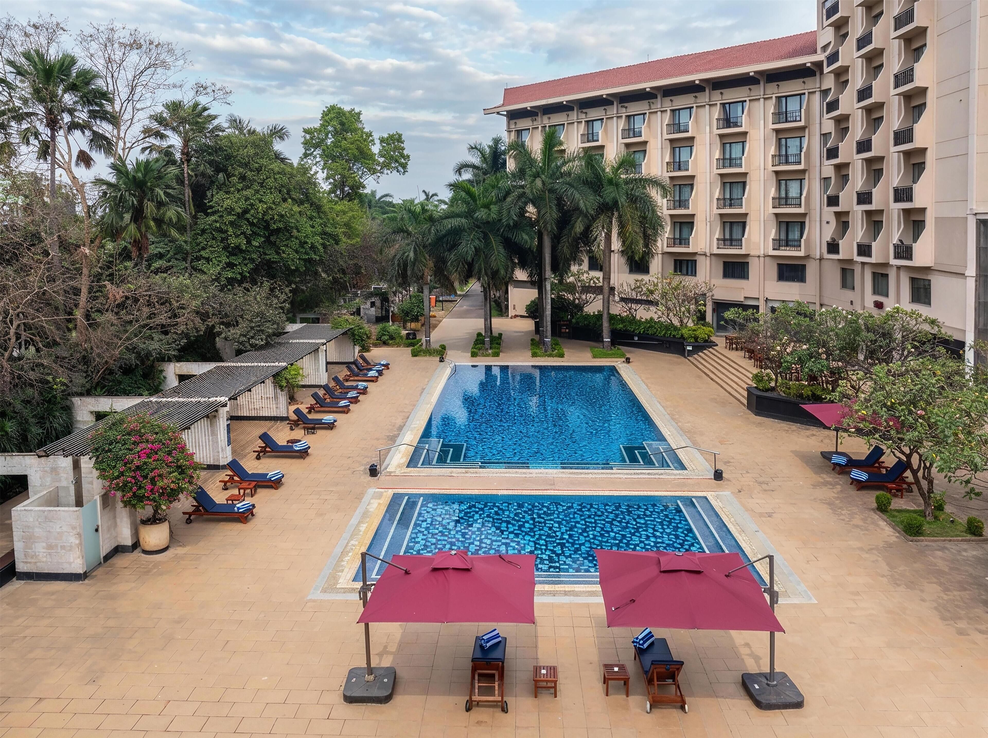 Un hotel con piscina, sillas de descanso y un edificio con balcones.