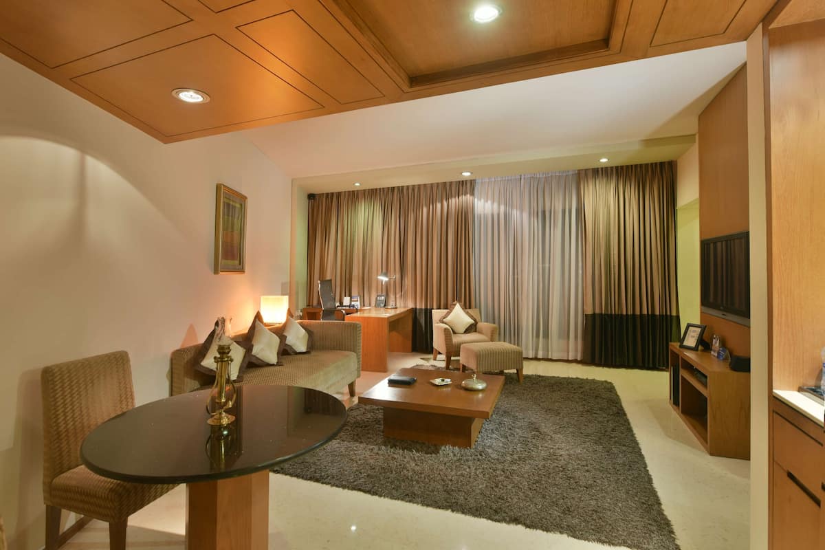 A modern living room with a glass-top dining table, a sofa, a coffee table, and a TV.
