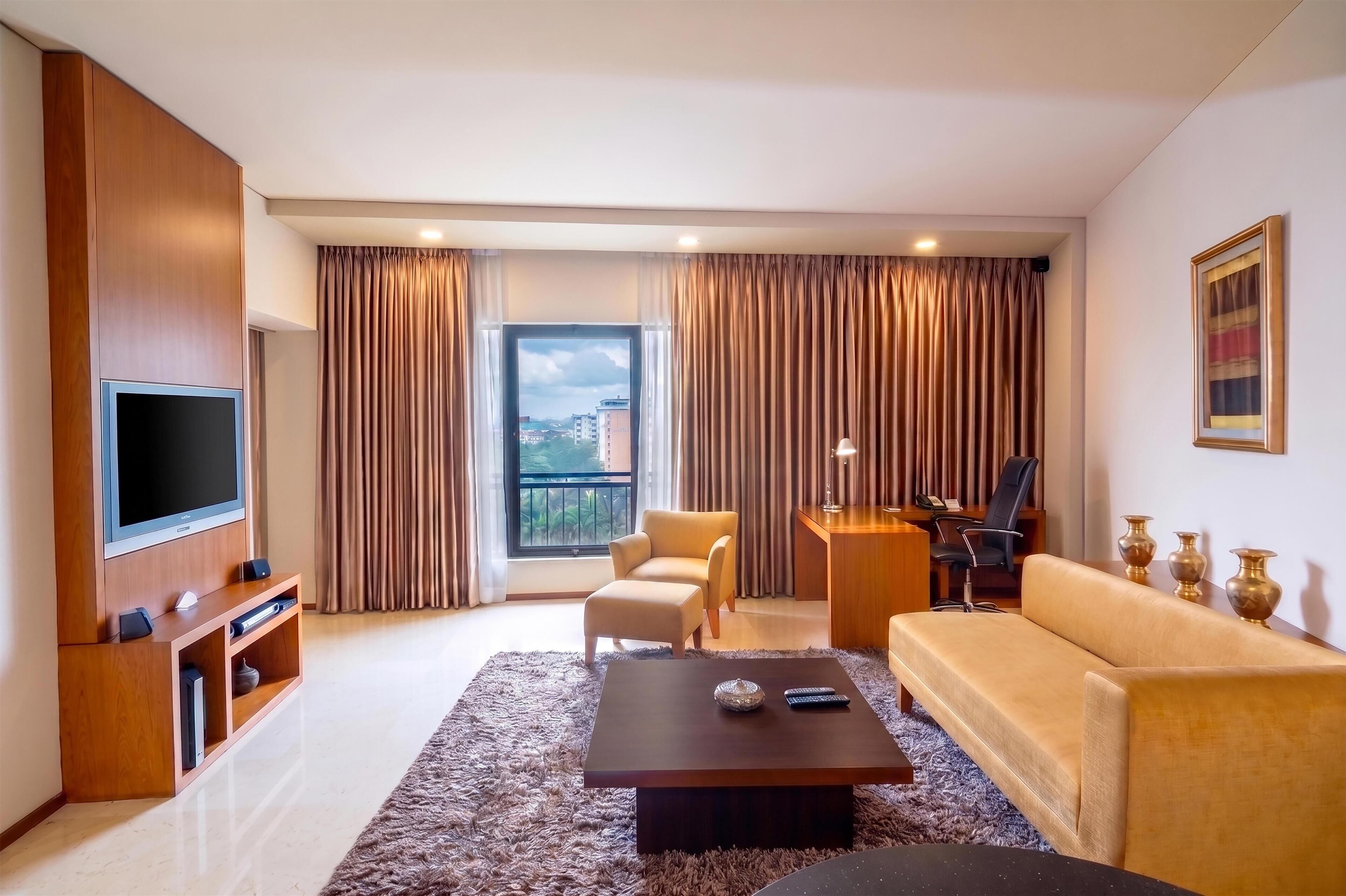 Una sala de estar moderna con televisor de pantalla plana, sofá, sillón y una mesa de centro.
