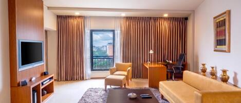 Una sala de estar moderna con televisor de pantalla plana, sofá, sillón y una mesa de centro.