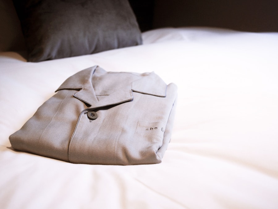 A neatly folded shirt on a bed with a pillow in the background.