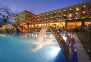 A hotel with a swimming pool, a water feature, and a covered area.