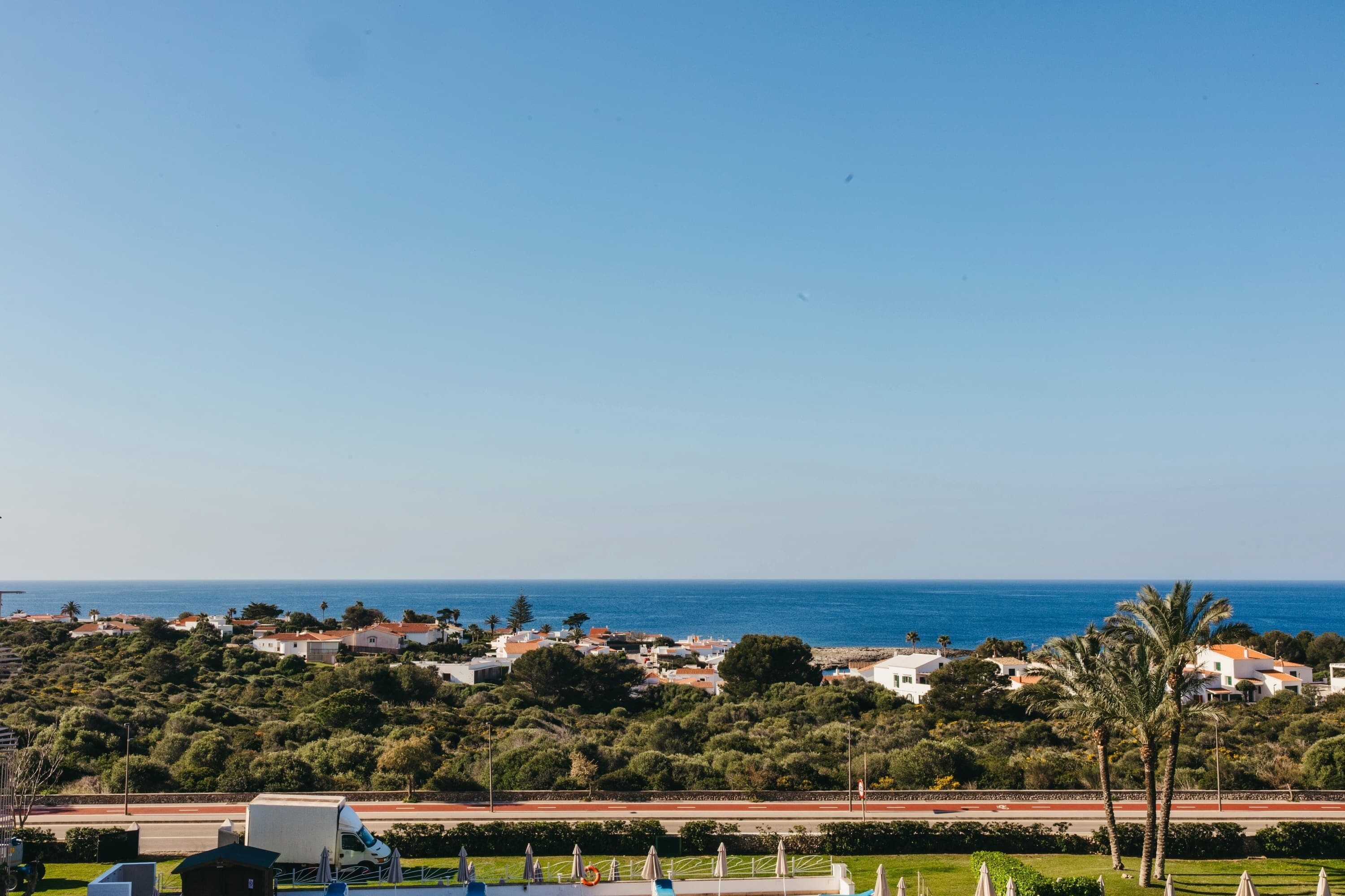 Eine Küstenstadt mit Blick auf das Meer, Häuser und eine Straße mit Palmen.