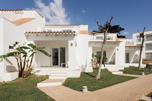 A modern building with a white facade, terracotta roof tiles, and a well-maintained lawn.