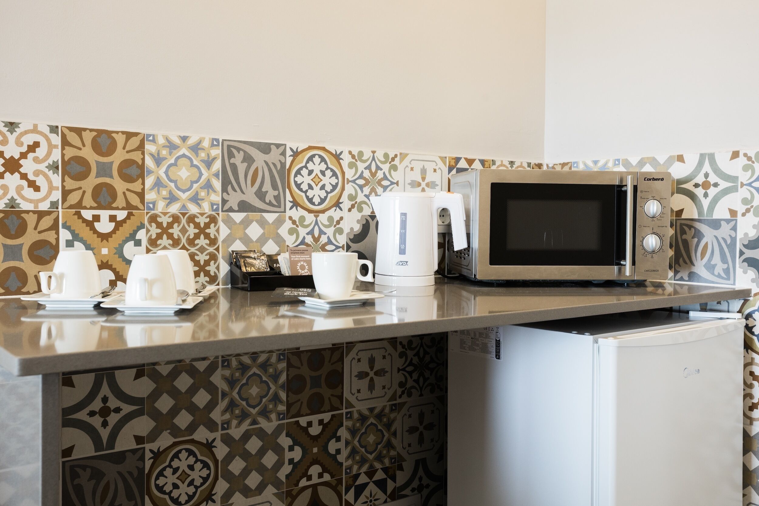 A kitchen with a microwave, coffee maker, and a refrigerator.
