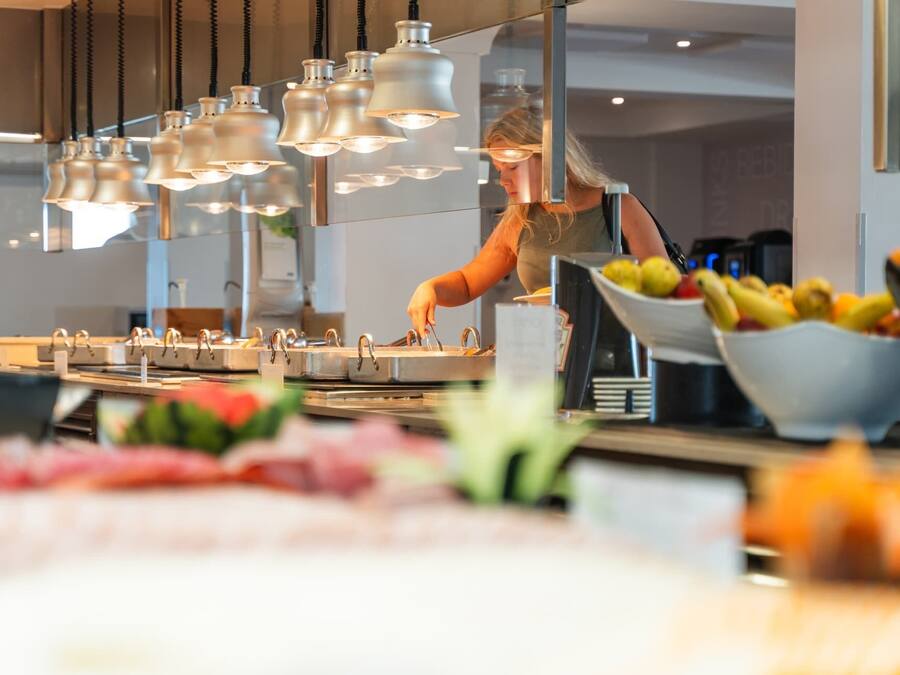 Una cocina moderna con electrodomésticos de acero inoxidable, un frutero y lámparas colgantes.