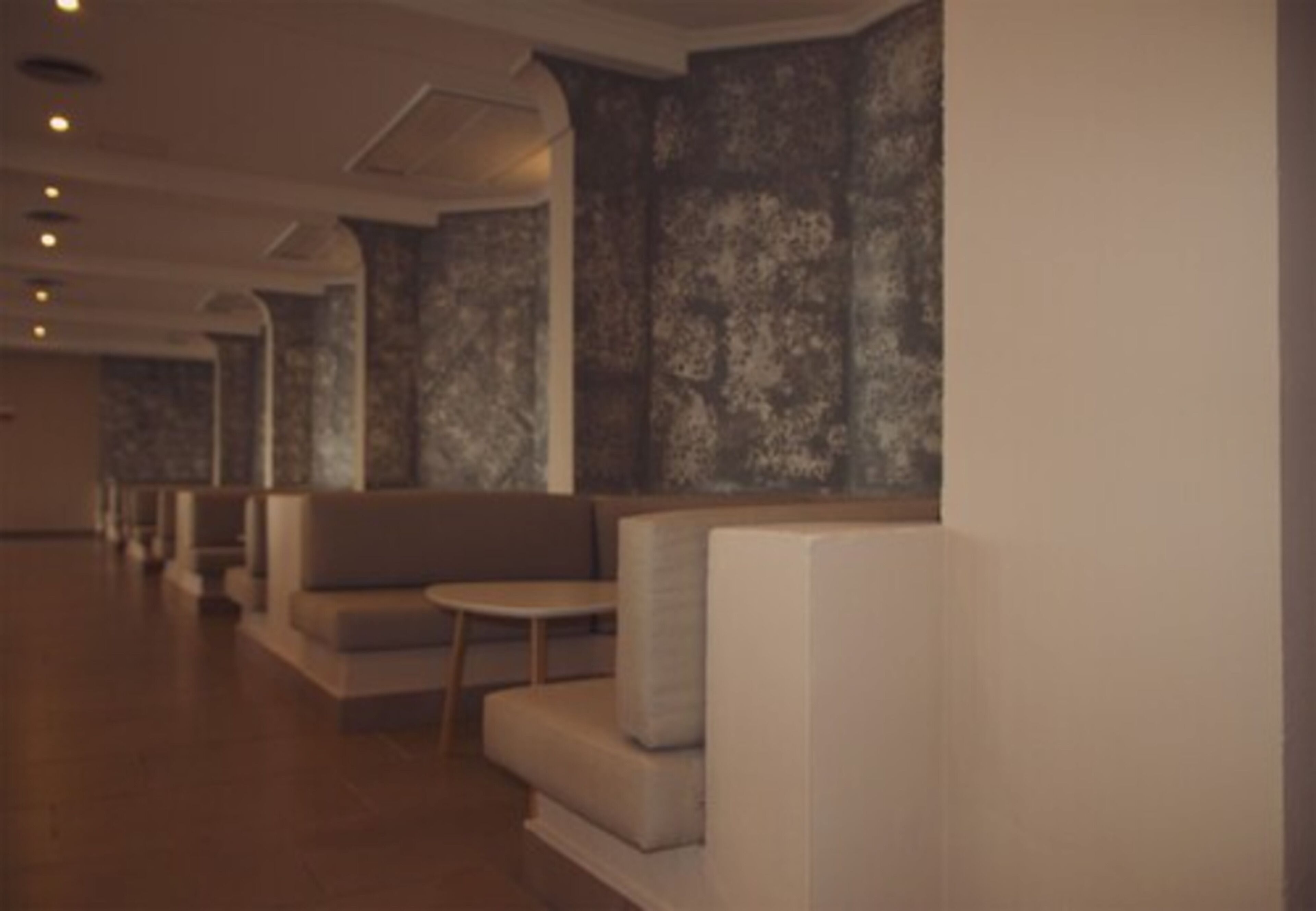 Un hall d’hôtel moderne, doté d’espaces aménagés avec des sièges et d’un mur orné de motifs.