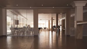 Un hall d’entrée spacieux, doté d’un plancher en bois, de grandes fenêtres et d’un espace détente avec des tables et des chaises.