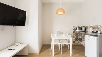 A small, modern kitchen with a white table, chairs, a microwave, and a refrigerator.