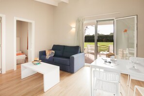A modern living room with a sofa, coffee table, and dining table. - Minura Hotel Sur Menorca (Sant Lluis)