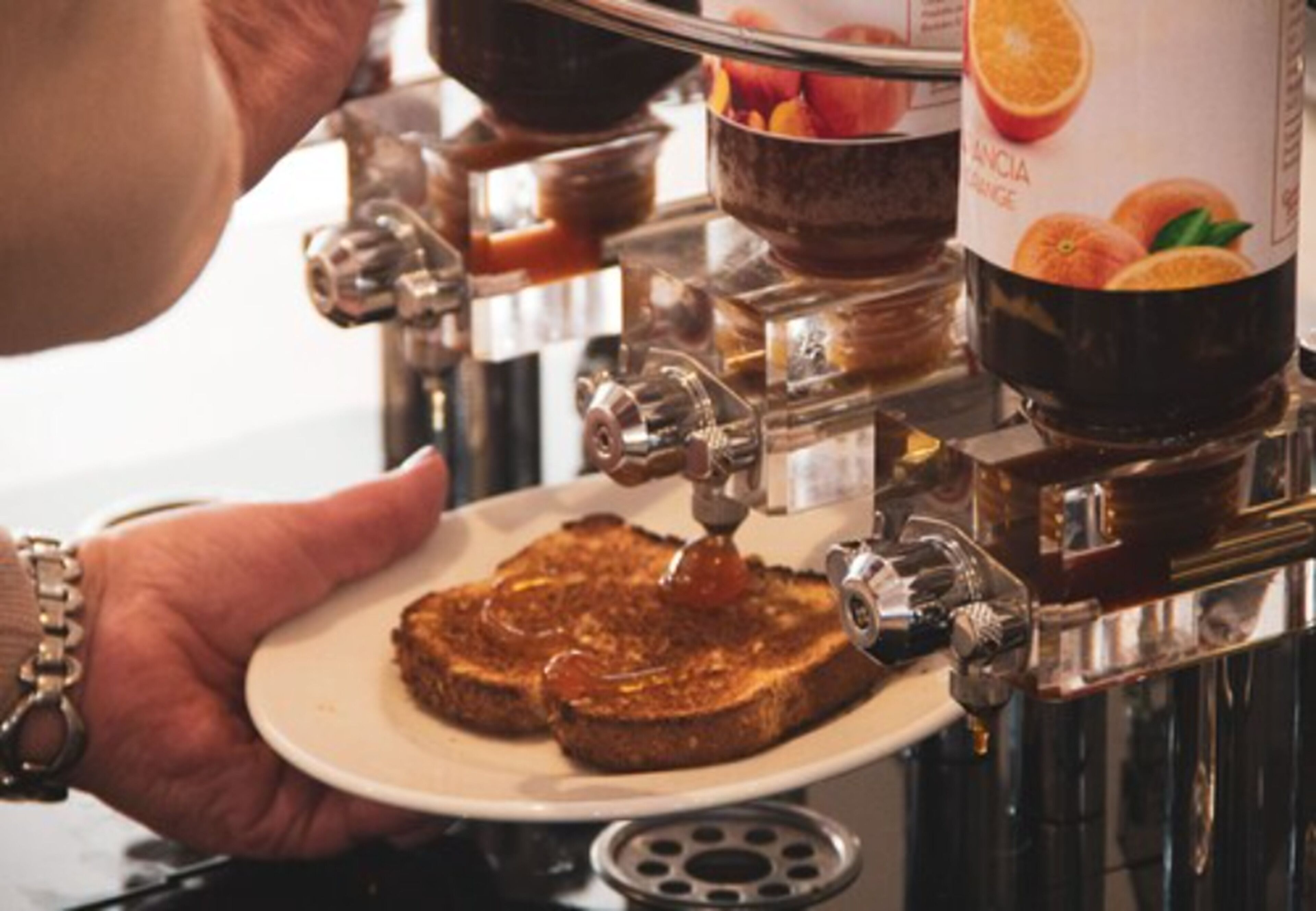 A person holding a plate with two slices of toast being drizzled with syrup.