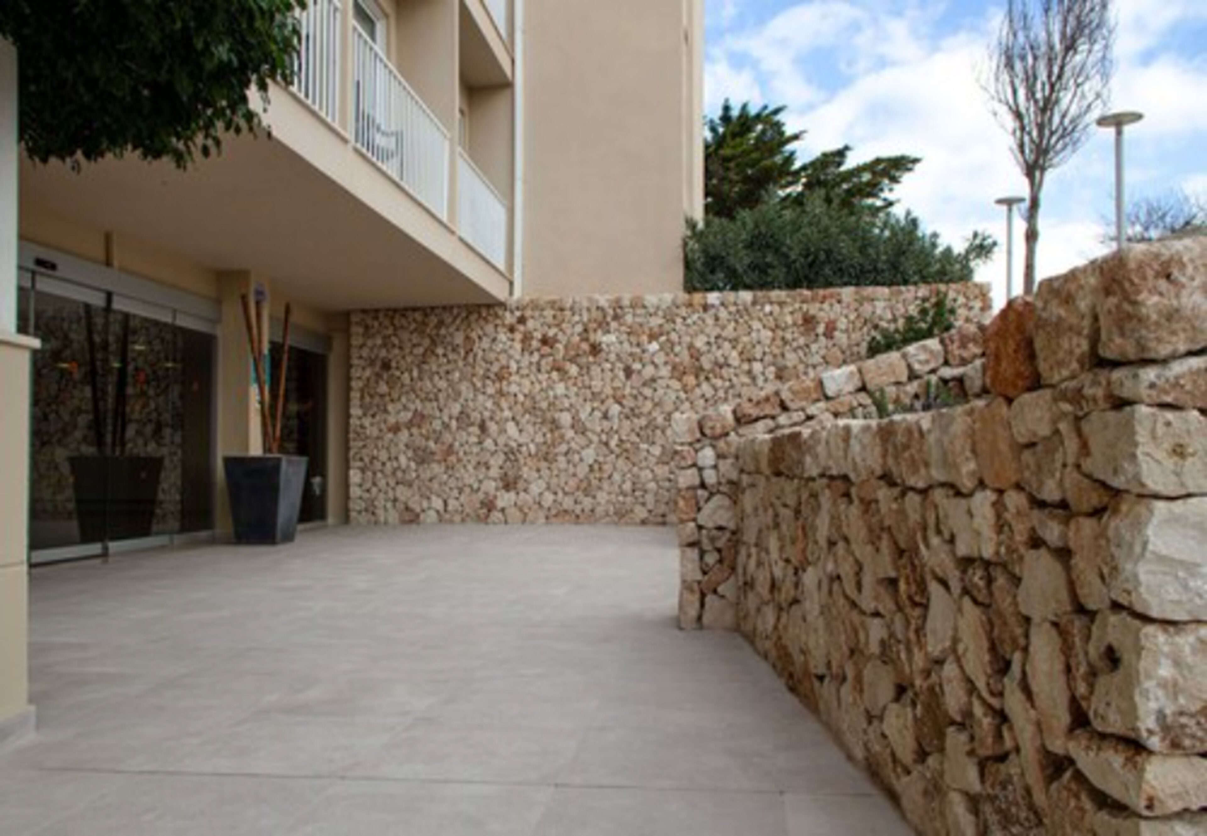 Un espace extérieur doté d’un mur en pierre et d’un bâtiment avec un balcon.