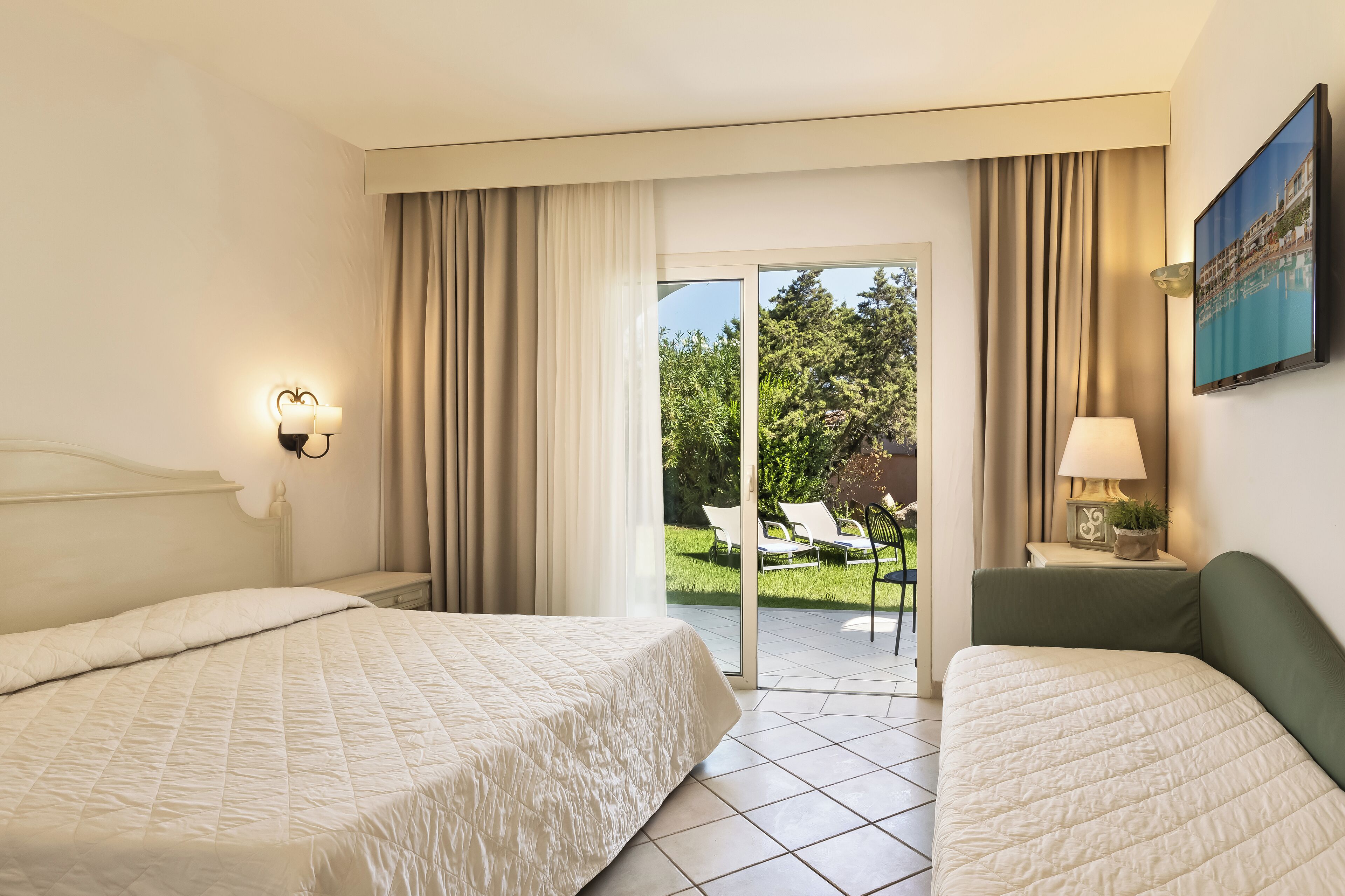 Une chambre d’hôtel avec deux lits, un balcon donnant sur un paysage verdoyant et un tableau accroché au mur.