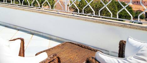 Un balcó amb mobles de vimetes i vista al mar.