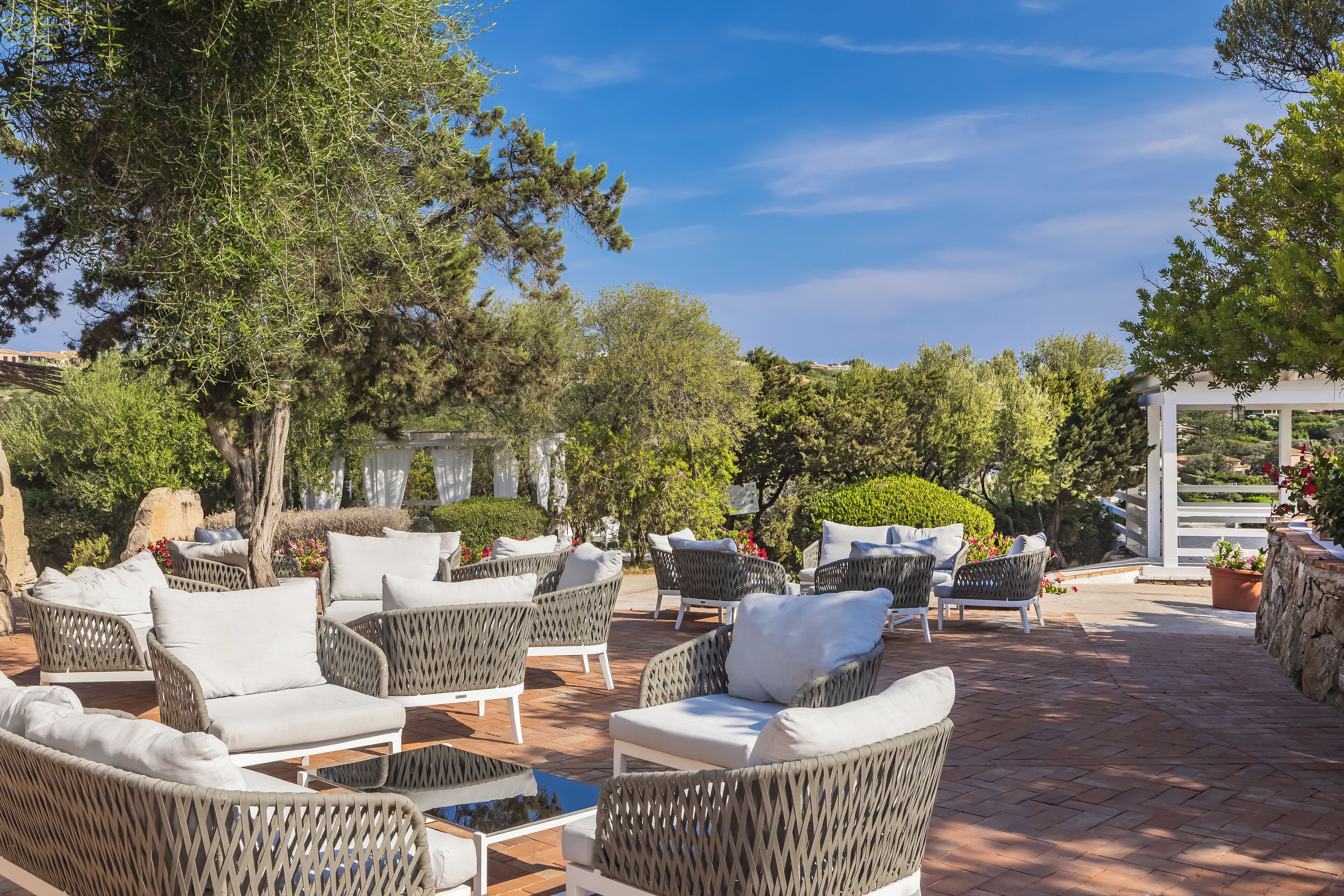 Une terrasse extérieure avec des meubles en osier et une pergola.