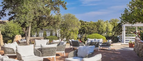 Une terrasse extérieure avec des meubles en osier et une pergola.
