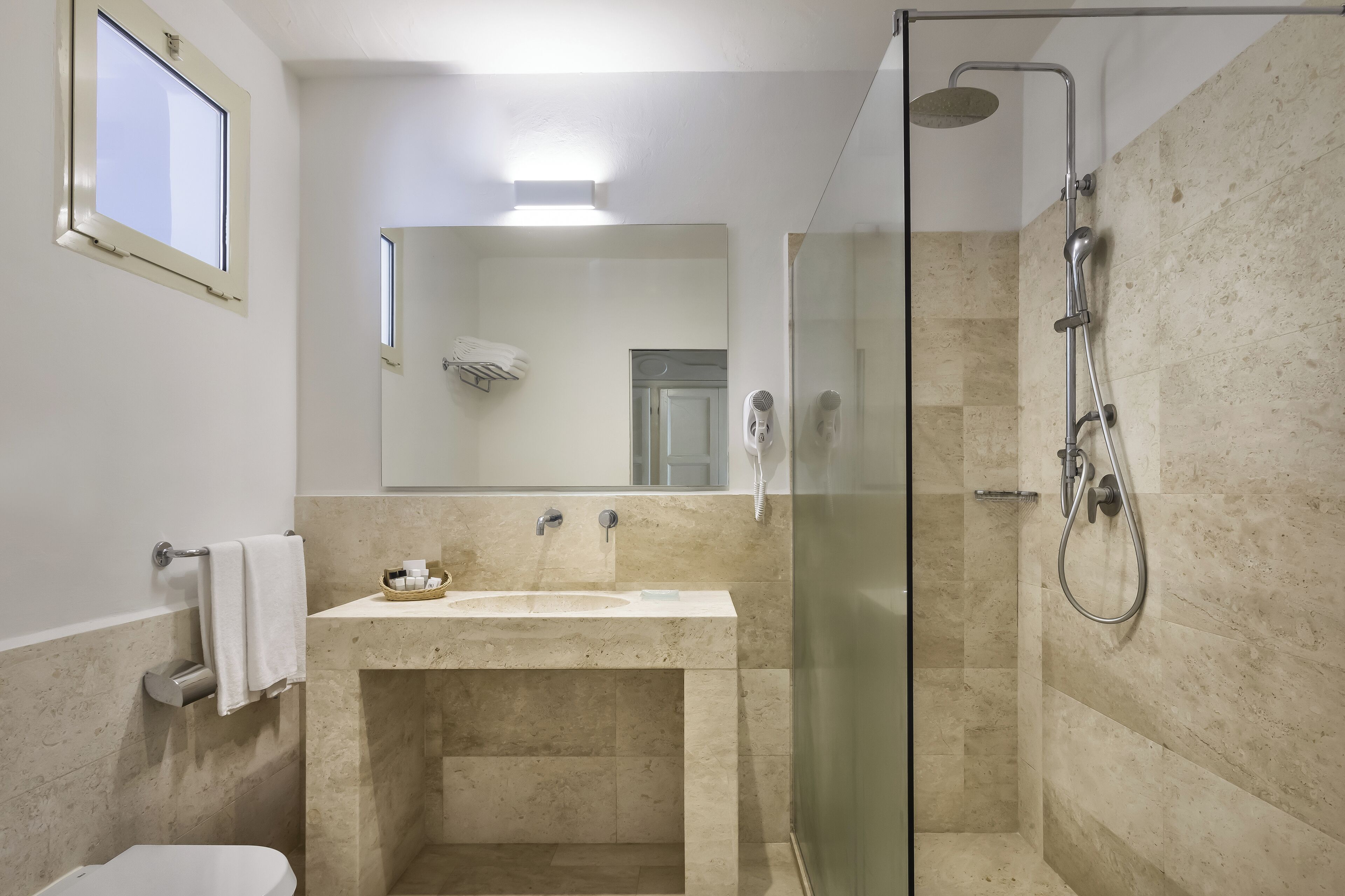 A bathroom with a glass-enclosed shower, a sink, and a toilet.