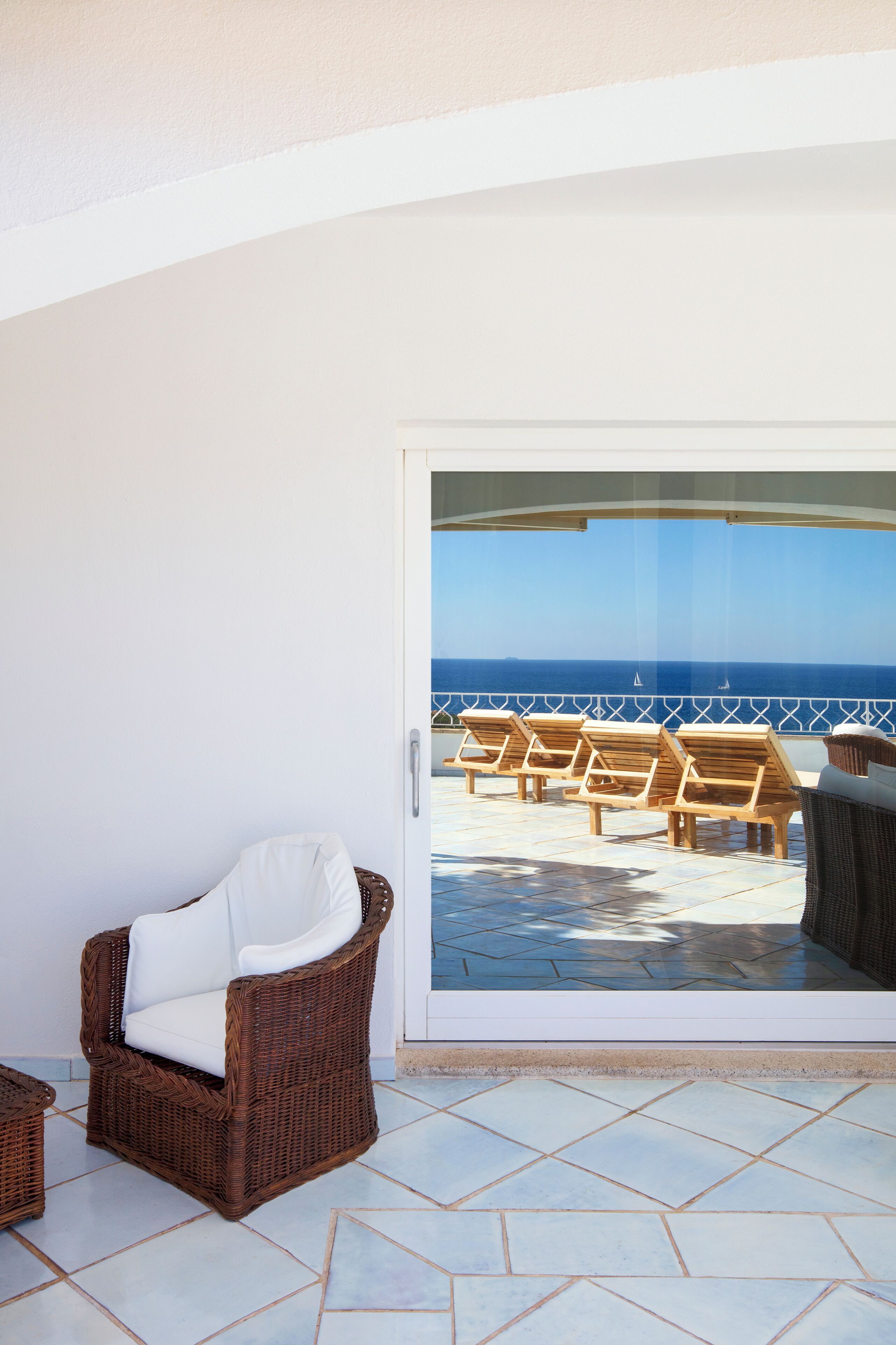 A balcony with wicker chairs and a view of the ocean.