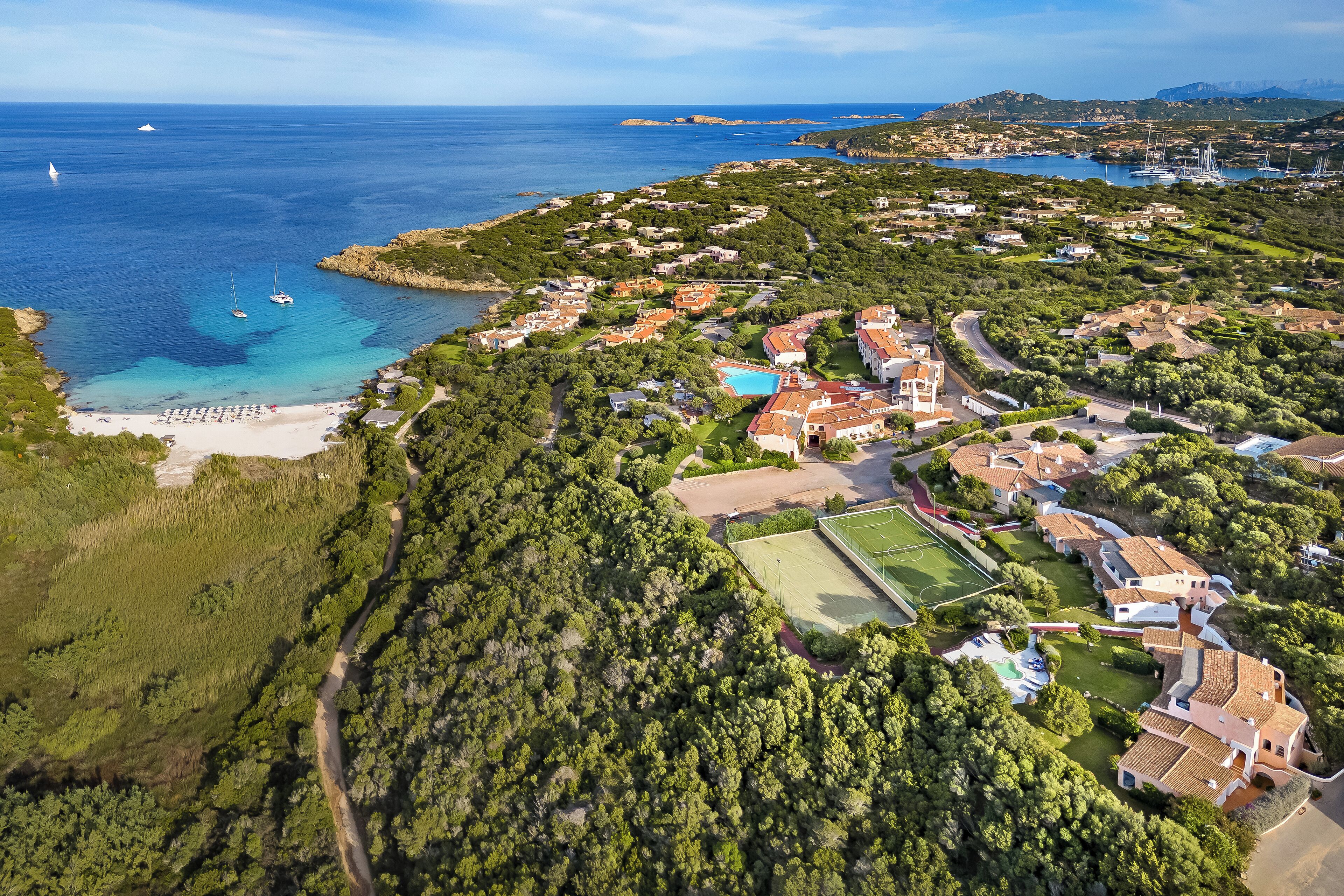 Vista aérea de una zona residencial costera con casas, una playa y un mar azul claro.