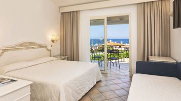 Une chambre d’hôtel avec deux lits, un balcon donnant sur la mer et un coin repas à l’extérieur.