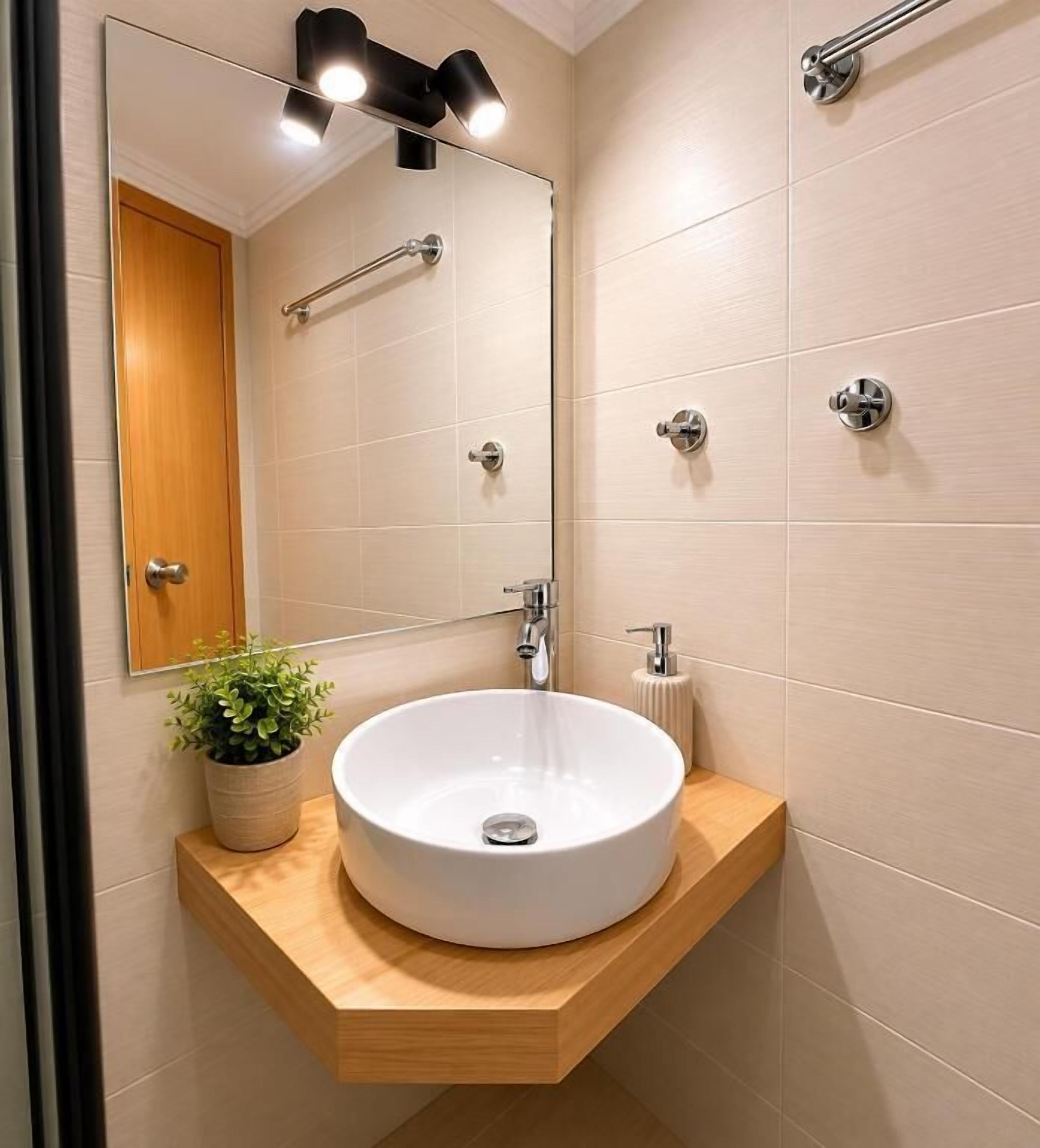 Une salle de bain avec un lavabo blanc, un miroir, un porte-serviettes et une plante en pot.