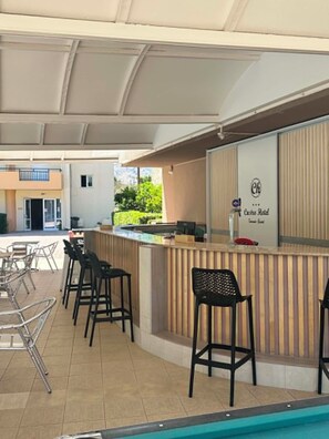 A poolside bar area with a counter, bar stools, and a pool. - Castro Hotel (Malevizi)