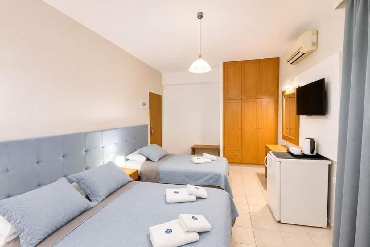 A hotel room with two beds, a TV, a desk, and a wardrobe.