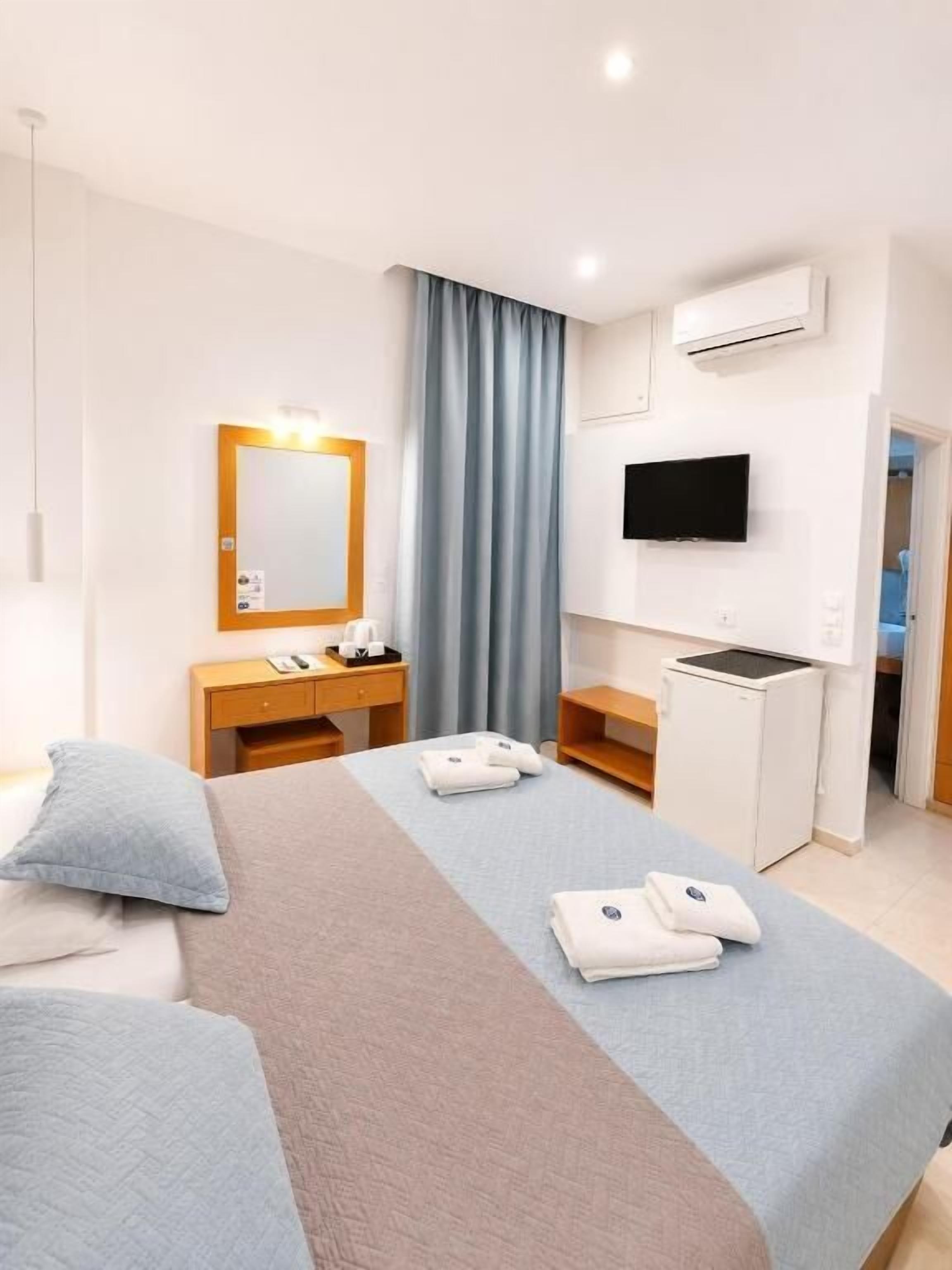 Habitación de hotel con dos camas, un escritorio, un televisor y un equipo de aire acondicionado.