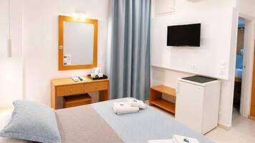 Habitación de hotel con dos camas, un escritorio, un televisor y un equipo de aire acondicionado.