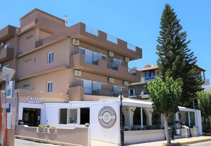 Ein Hotel mit schlichter Fassade, Balkonen und einem Restaurant mit Außenbereich.