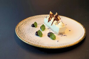 Un dessert su un piatto con foglie di menta e decorazioni al cioccolato.