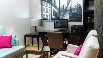 A modern living room with a sofa, armchair, coffee table, desk, and a flat-screen TV.