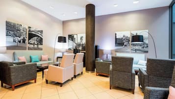 Un vestíbulo moderno con un sofá, sillones, una mesa de centro y un pilar grande.