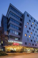 Um hotel Courtyard Marriott com design moderno, destacando uma entrada imponente com portas de vidro e uma galeria coberta.