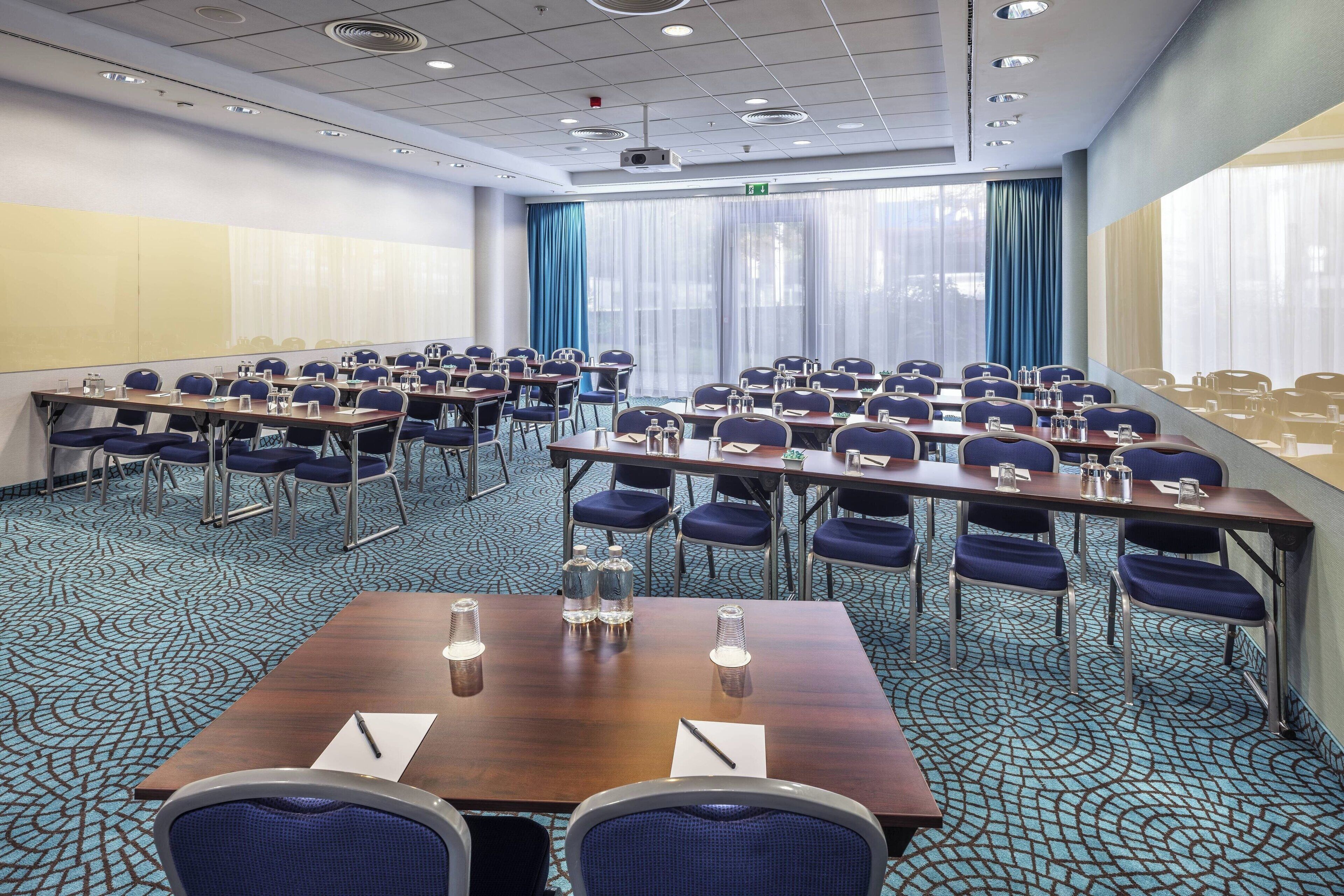 A conference room with multiple tables and chairs, equipped with water bottles and nameplates.