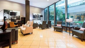 Un vestíbulo espacioso con muebles modernos, ventanas amplias y obras de arte en las paredes.