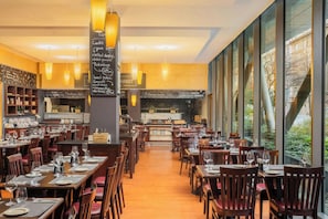 Restaurante com várias mesas, cadeiras e um menu em lousa.