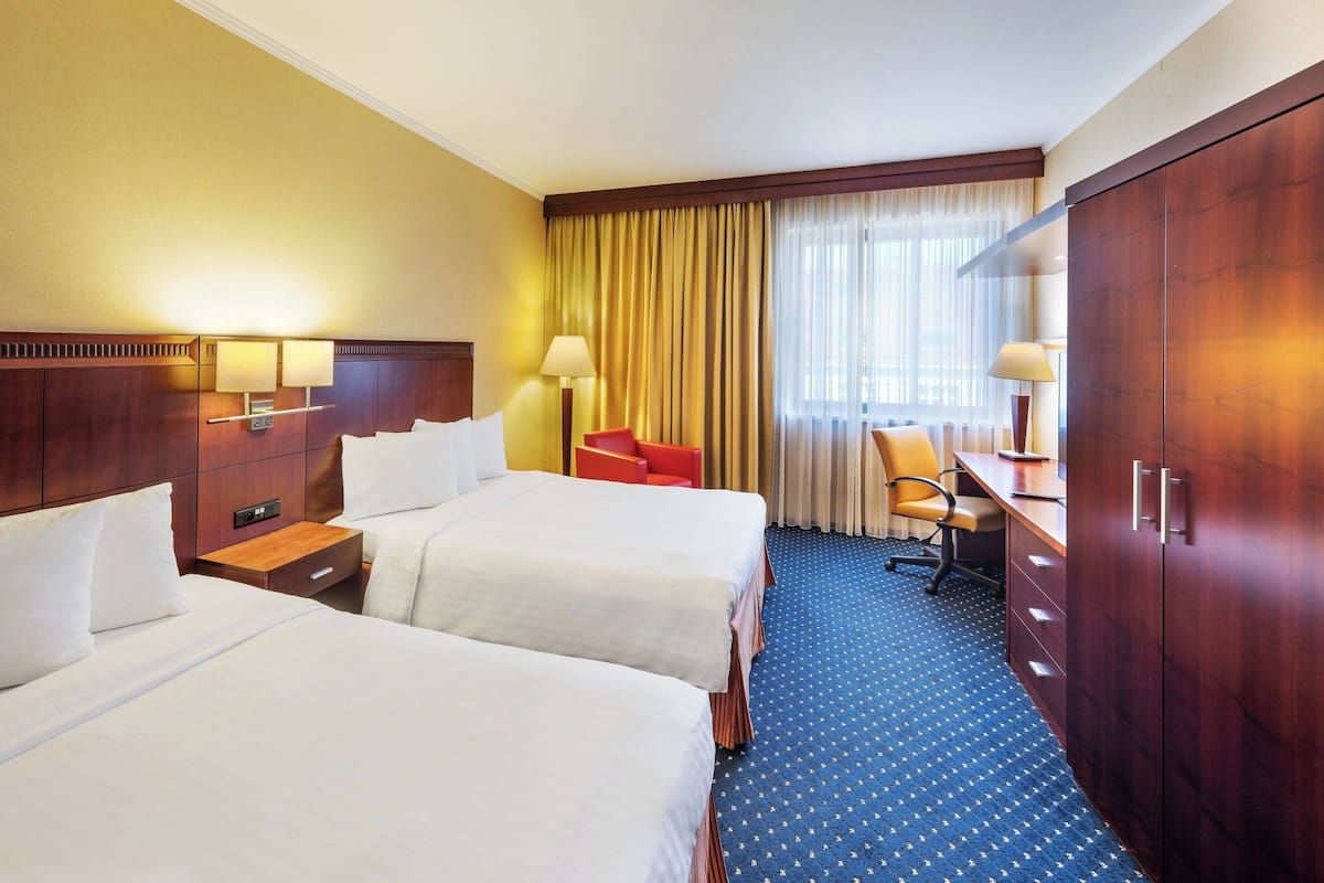 Ein Hotelzimmer mit zwei Betten, einem Schreibtisch, einem Stuhl und einem Kleiderschrank.