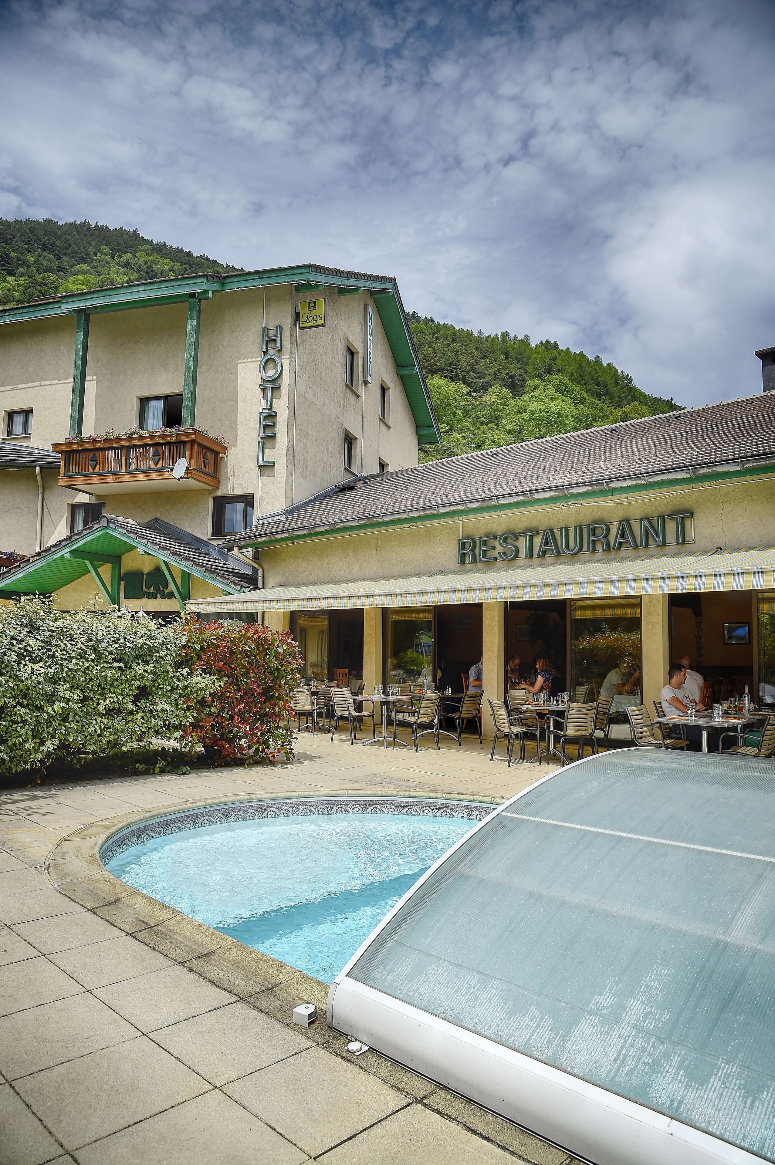 A restaurant with outdoor seating and a swimming pool.