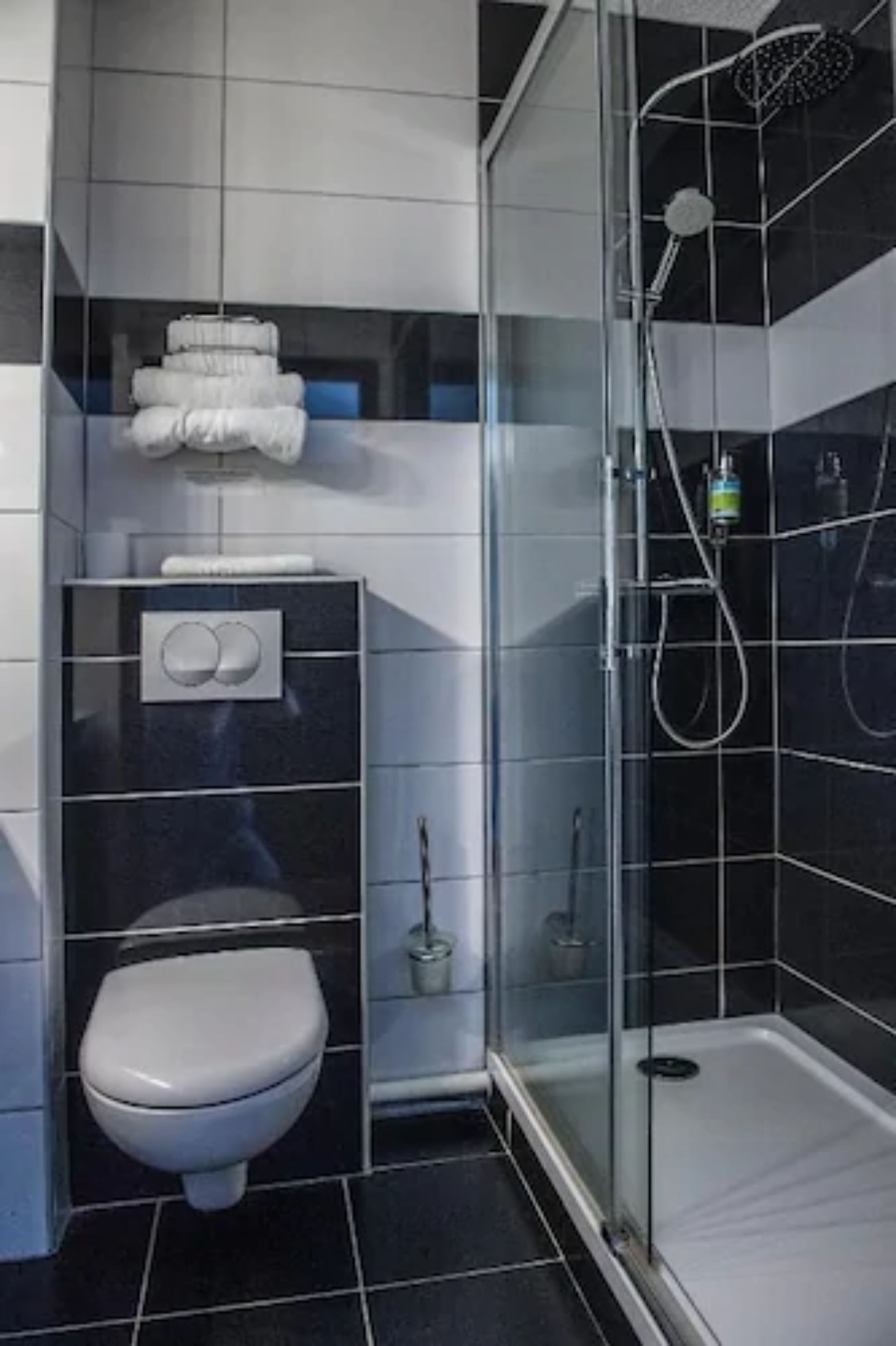 Un baño moderno con inodoro, cabina de ducha de vidrio y lavamanos con toallero.