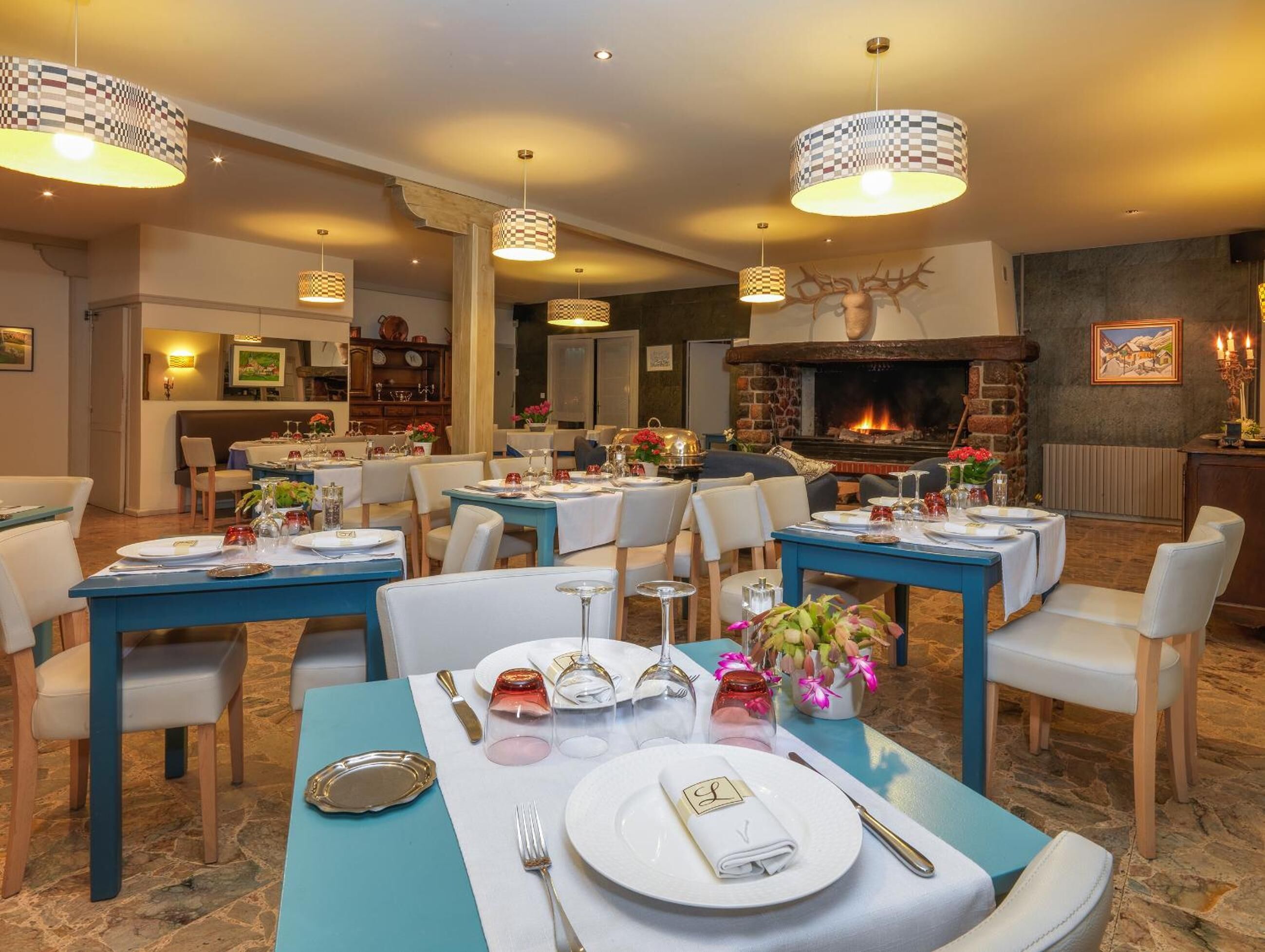 Un restaurante con mesas dispuestas para comer, una chimenea y lámparas colgantes.