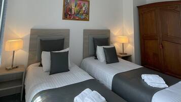 Une chambre d’hôtel avec deux lits, un tableau au mur, un climatiseur et une armoire.