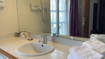 A bathroom with a sink, mirror, towel rack, and a window with curtains.