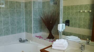 A bathroom with a bathtub, a sink, a mirror, and a wall-mounted soap dispenser.