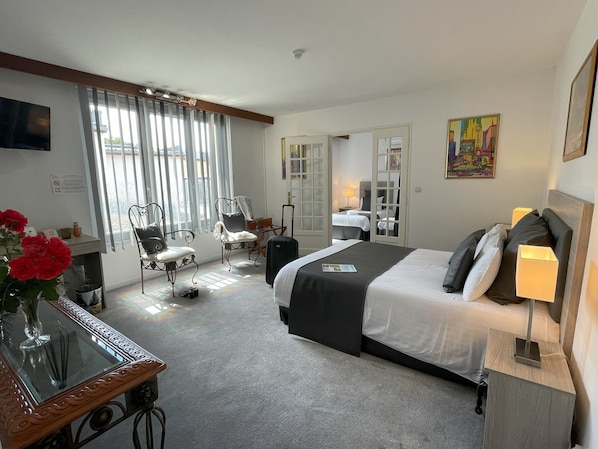 A hotel room with a bed, a desk, a chair, a TV, and a window with curtains. - The Originals Boutique, Hôtel Clos St Marie (Nevers)