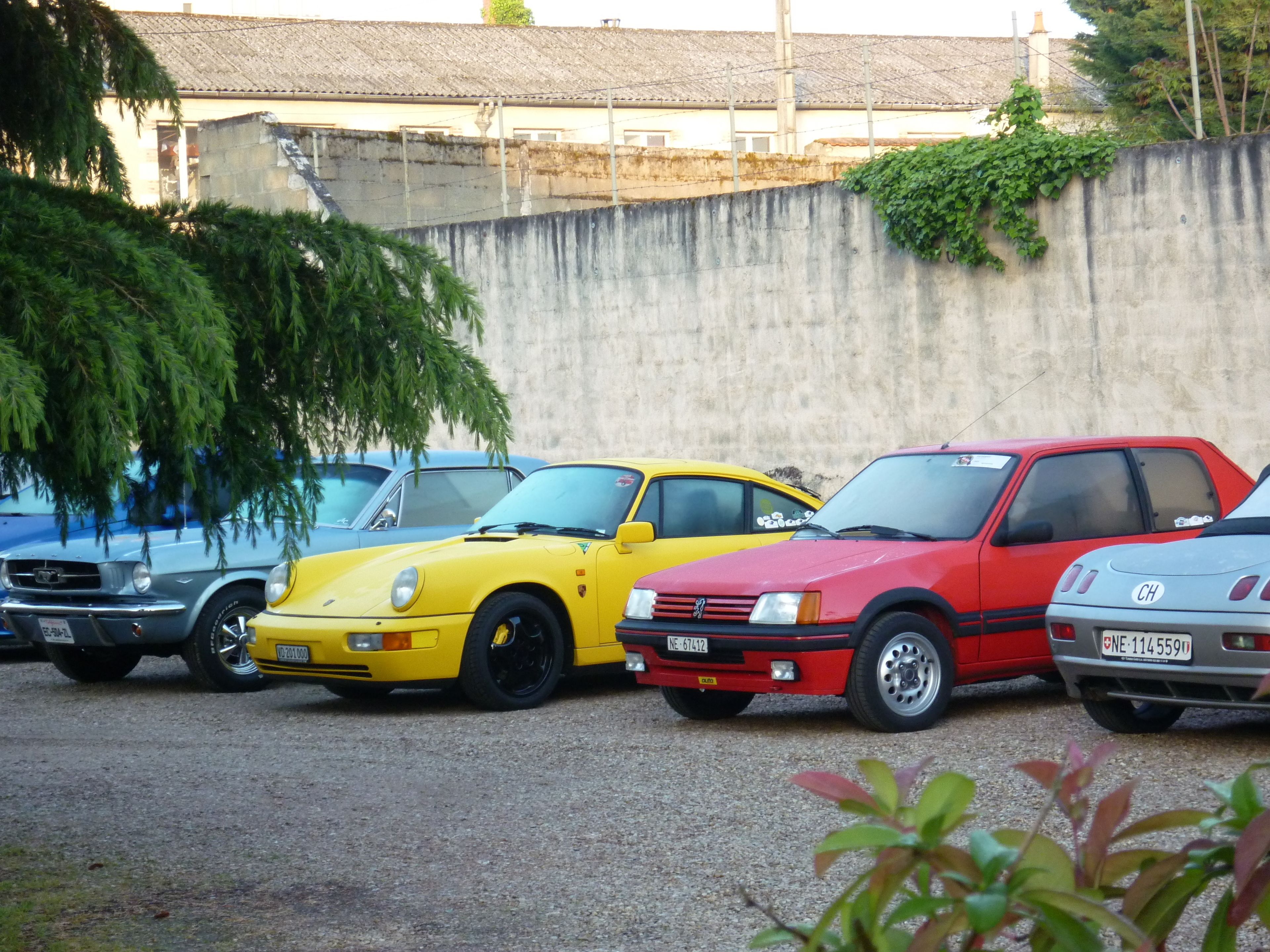 Un estacionamiento con varios autos, incluyendo uno amarillo y uno rojo.